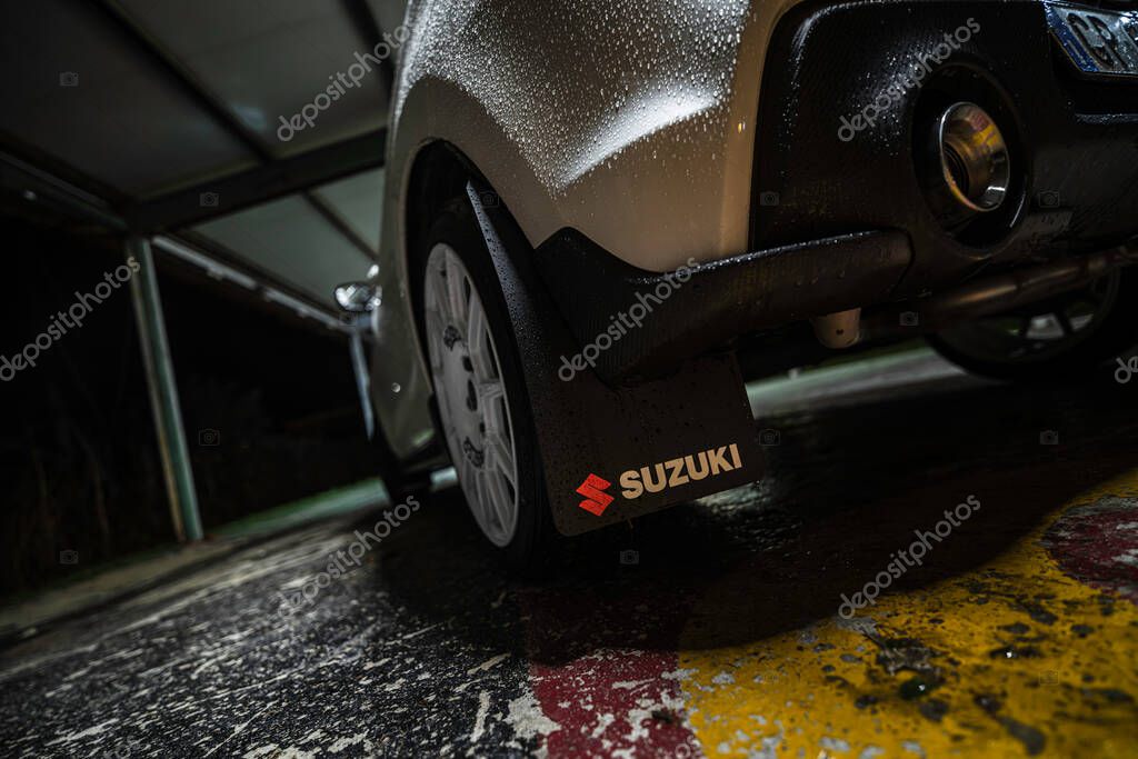 Rome, italy 30 september 2025: suzuki parked at night after rain, low-angle close-up of wet wheel, mudflap and wheel arch reflecting streetlight on asphalt