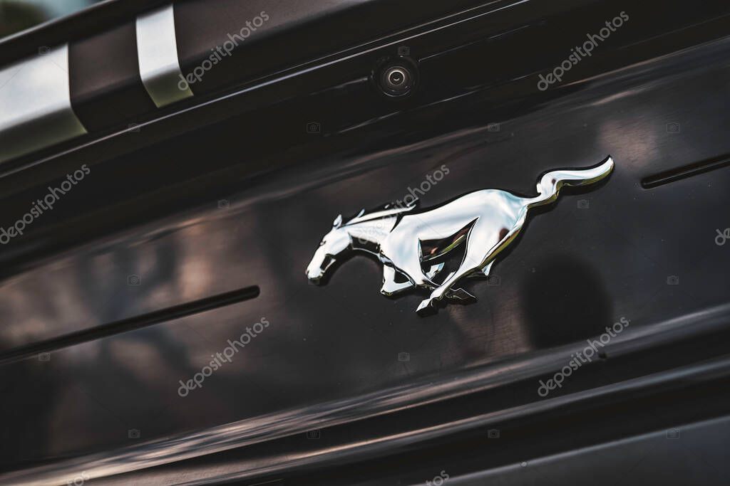Rome, italy 30 september 2025: silver chrome mustang running horse emblem mounted on glossy black trunk, close-up detail showcasing iconic american muscle car power