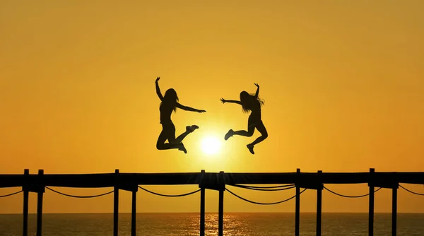Two Silhouetted Females Leap Air Figures Outlined Stunning Sunset Sky — Stock Photo, Image