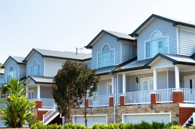 Çifte katlı evlerin ön manzarası, kendine özgü hava tahtasının kaplamaları ve kıvrımlı metal çatılarıyla karakterize edilir.