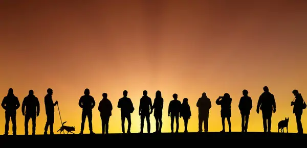 Group of peoples silhouettes stands against the awe-inspiring backdrop of a winter sunset