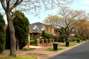 Melbourne bölgesindeki tipik bir yaz sokağı, düzgünce yerleştirilmiş çöp bidonları, günlerin toplanması için hazır bekliyor.