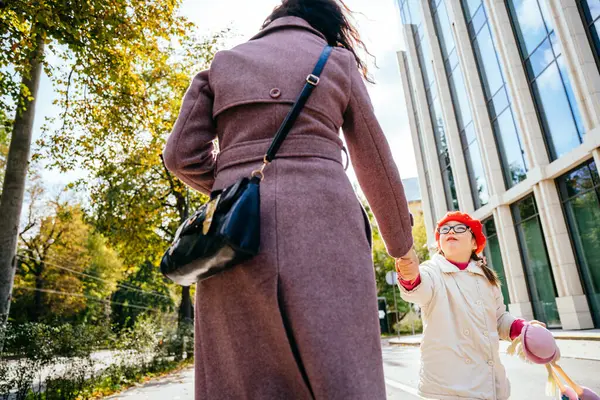 赤い赤いかわいい少女は 眼鏡でベレーとコートを着て フロリックし 秋の晴れた日の市街の屋外で彼女の認識できない母親と遊ぶ — ストック写真