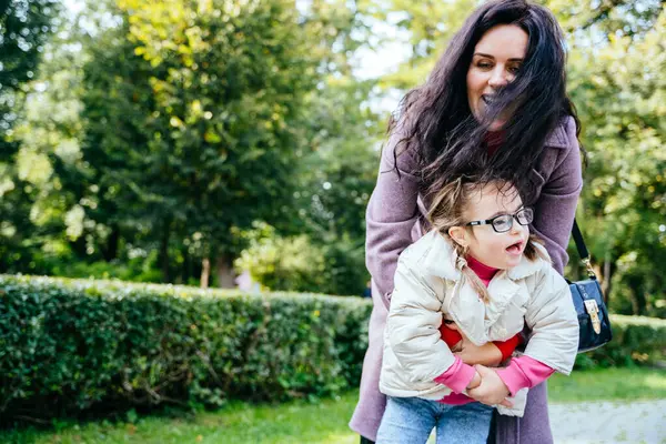 小さな女の子と遊び 秋の日の屋外で公園でジャンプする若い母親 子供は親からの愛を感じます 幸せな家族の瞬間コンセプト — ストック写真