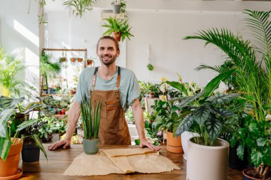 Önlük takan yakışıklı beyaz adam çiçekçide yeşillik özenle saksı bitkisini kağıda sarıyordu. Samimi çiçekçideki işinden zevk alıyor. Şehir ormanı ve bitki ebeveyni kavramı.