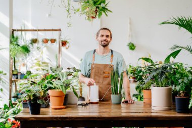 Küçük işletme girişimcisi. Kafkasyalı bir satıcının portresi, çiçekçide saksı bitkisi satan bir çalışan. Şehir ormanı ve bitki ebeveyni kavramı.