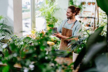 Küçük işletme girişimcisi. Üniforma giyen yetişkin bir beyaz adam yerel bitkilerle ilgileniyor şehir ormanları ve bitki yetiştirme kavramı..