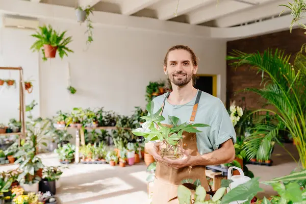 Çiçekçide poz veren sakallı bir çiçekçinin portresi. Küçük işletme girişimcisi.