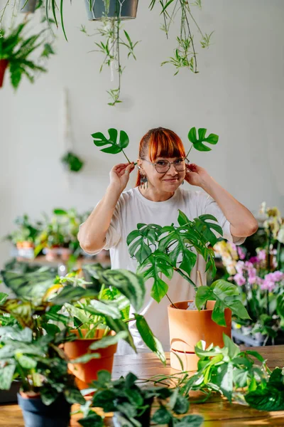 Bitkilerle ilgilenen bahçıvanlarla. Milenyum kadın bahçıvan kızıl saçlı genç bir bitkiyi kulaklarında iki canavar yaprağı ile tutuyor. Bitkileri budamak için konsept