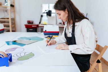 Çalışma odasındaki vitraylı pencereler için Sketch 'le çalışan genç bir kadın sanatçı. Sanat, el yapımı, hobiler ve el sanatları konsepti.