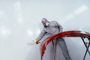 Otantik atış. Araba boyacısı, oda boyacısı, araba servisinde araba tamponu boyuyor..