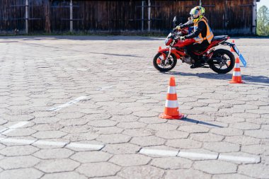 Kasklı kadın sürücü motosiklet dersleri alıyor ve sürüş alıştırması yapıyor. slalom turuncu konilerin arasından motosikletli motor pistinde. Motosiklet sürüş okulu.