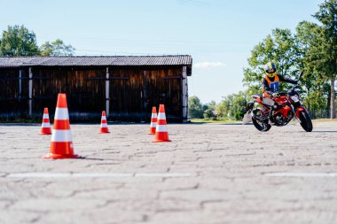 Kasklı kadın sürücü motosiklet dersleri alıyor ve sürüş alıştırması yapıyor. slalom turuncu konilerin arasından motosikletli motor pistinde. Motosiklet sürüş okulu.