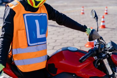 Motosiklet sürüş okulu kavramı. Motosiklette oturan tanınmayan bir kadın ehliyet almadan önce araba kullanmayı öğreniyor..