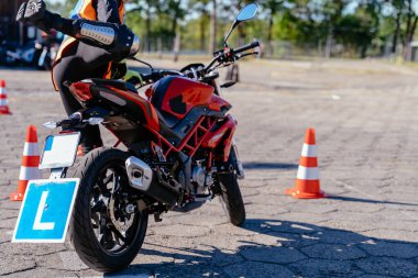 Motosiklet sürüş okulu kavramı. Tanınmayan bir kız, koruyucu dizlik takan motosikletli bir okul öğrencisi, motosikletin üstünde oturuyor.