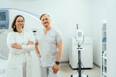 Tıbbi kadın uzmanın portresi ve MRI tarayıcısının önünde duran kendine güvenen beyaz erkek doktor..