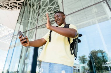 Sırt çantalı bir gezgin cep telefonuyla fotoğraf çekiyor ya da uluslararası havaalanı terminalinde video görüşmesi yapıyor. Uçak ya da otobüs yolculuğu kavramı.