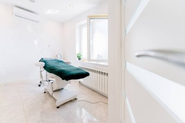 Güzeller Salonu 'nda masaj masası olan şık bir oda. Yeşil masası ve beyaz duvarları olan bir sağlık ofisi..