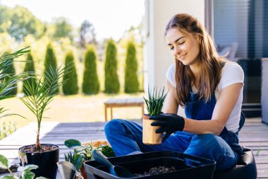 Profesyonel, sevimli bayan, terasta bahçe işleriyle uğraşırken güneşli bahar günlerinde tatlı yüzlü, sulu bir tencere tutar..