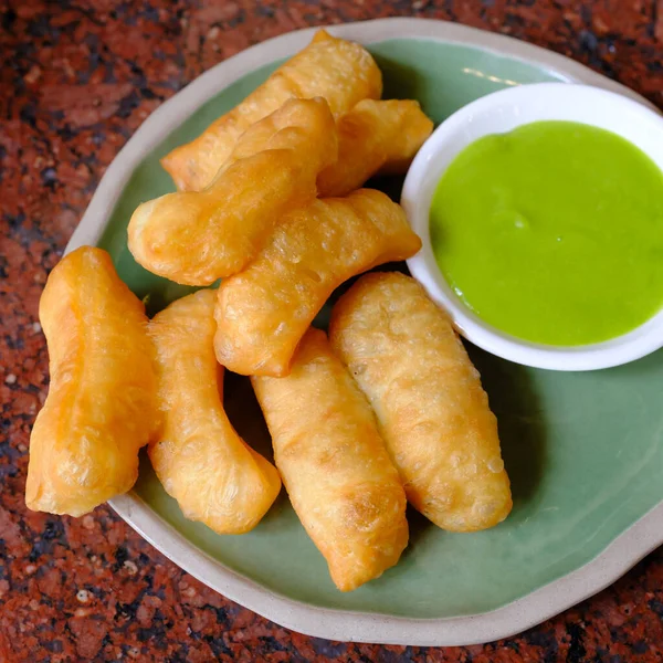deep-fried dough stick with pandan thai custard on the red table