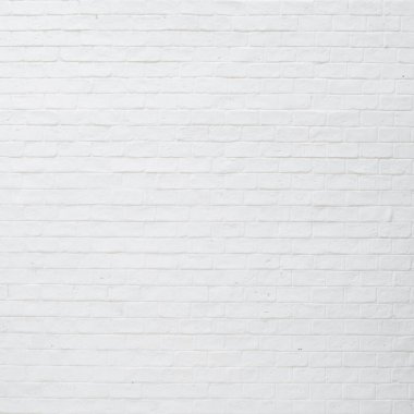 Kahve dükkanının önünde beyaz tuğladan bir duvar. 