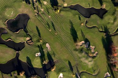 Bir golf sahasının bir kısmını gösteren havadan çekilmiş fotoğraflar. 