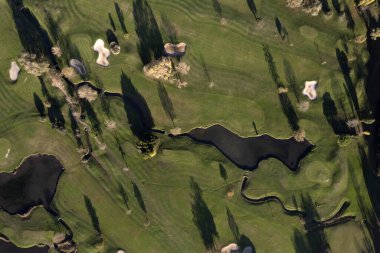 Bir golf sahasının bir kısmını gösteren havadan çekilmiş fotoğraflar. 