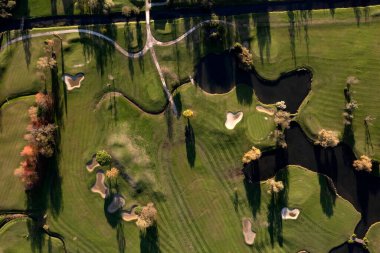 Bir golf sahasının bir kısmını gösteren havadan çekilmiş fotoğraflar. 