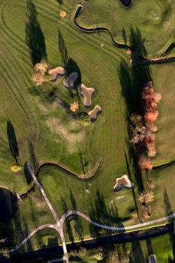 Bir golf sahasının bir kısmını gösteren havadan çekilmiş fotoğraflar. 