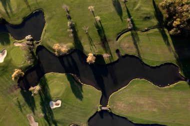 Bir golf sahasının bir kısmını gösteren havadan çekilmiş fotoğraflar. 