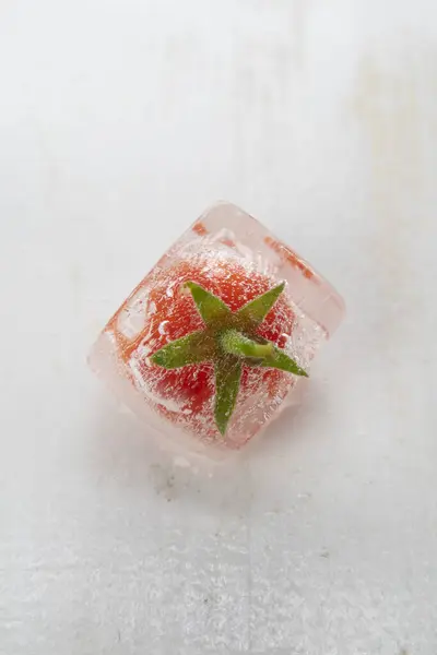 Photographic documentation of some small tomatoes inside an ice cube