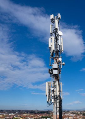 Cep telefonu sinyali yineleyici anten ve kablolar ile, metal bir direkte, mavi gökyüzüne ve bulutlara karşı. 