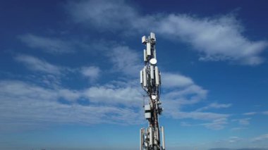 Mavi gökyüzü ve bulutlara karşı metal bir direkte antenli bir cep telefonu sinyal yineleyicisinin videosu.. 