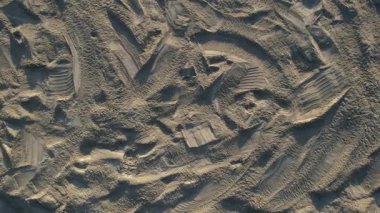 Yüzeydeki insan ve araçlardan rahatsız olan kumlu bir plajın detaylı hava görüntüsü.. 