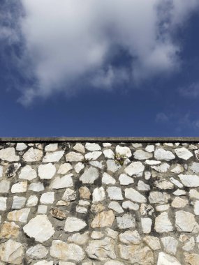 Açık gri çimentoyla tutturulmuş beyaz, gri ve kahverengi düzensiz taşlardan oluşan bir duvarın fotografik belgeleri.. 