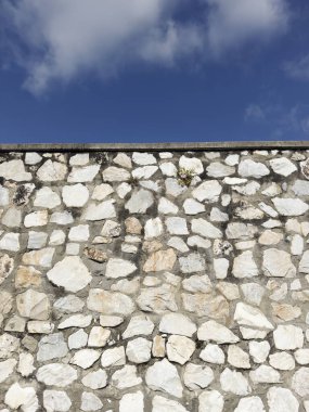 Açık gri çimentoyla tutturulmuş beyaz, gri ve kahverengi düzensiz taşlardan oluşan bir duvarın fotografik belgeleri.. 
