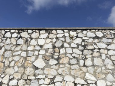 Açık gri çimentoyla tutturulmuş beyaz, gri ve kahverengi düzensiz taşlardan oluşan bir duvarın fotografik belgeleri.. 
