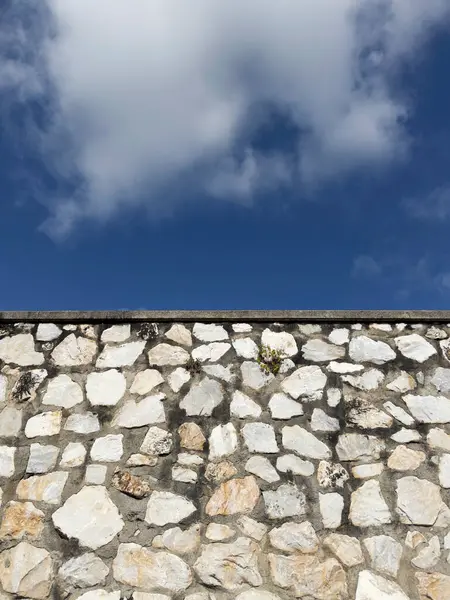 Açık gri çimentoyla tutturulmuş beyaz, gri ve kahverengi düzensiz taşlardan oluşan bir duvarın fotografik belgeleri.. 