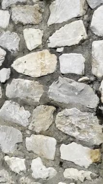 Açık gri çimentoyla tutturulmuş beyaz, gri ve kahverengi düzensiz taşlardan oluşan bir duvarın video dökümanları. 