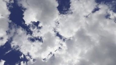 Zaman aşımı video dökümanları beyaz ve gri bulutların hızlı hareketlerini gösteriyor. Bu bulutlar mavi gökyüzünü gün ışığı noktasıyla örtüyor ve ortaya çıkarıyor..