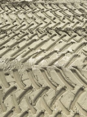 Aydınlık ve düzgün kumlu yüzeye basılmış lastik izlerinin fotoğraflı belgesi.