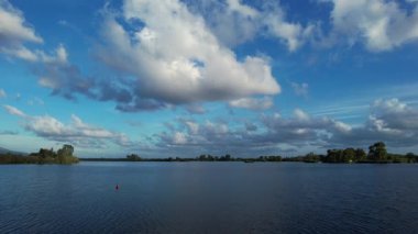 Durgun bir su kütlesinin, beyaz ve kabarık bulutlu mavi gökyüzünü yansıtan, barış ve sonsuz doğal güzellikte bir atmosfer yaratan video dökümanları.. 