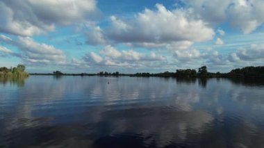 Durgun bir su kütlesinin, beyaz ve kabarık bulutlu mavi gökyüzünü yansıtan, barış ve sonsuz doğal güzellikte bir atmosfer yaratan video dökümanları.. 