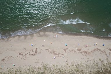 Yüzen ve renkli şemsiyeli doğal bir sahilin havadan görünüşü, yaz, özgürlük ve deniz kıyısında dinlenme.. 