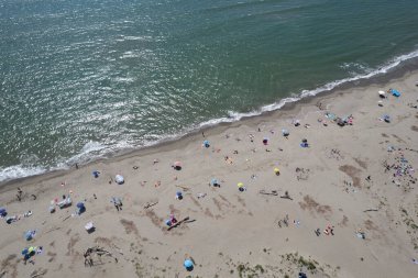 Yüzen ve renkli şemsiyeli doğal bir sahilin havadan görünüşü, yaz, özgürlük ve deniz kıyısında dinlenme.. 