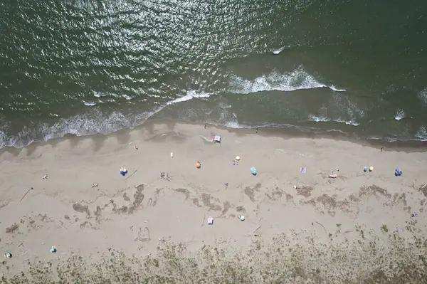 Yüzen ve renkli şemsiyeli doğal bir sahilin havadan görünüşü, yaz, özgürlük ve deniz kıyısında dinlenme.. 