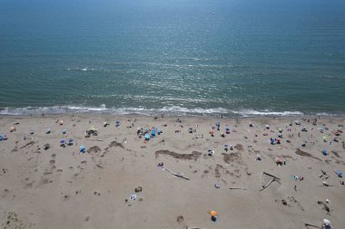 Yüzen ve renkli şemsiyeli doğal bir sahilin havadan görünüşü, yaz, özgürlük ve deniz kıyısında dinlenme.. 