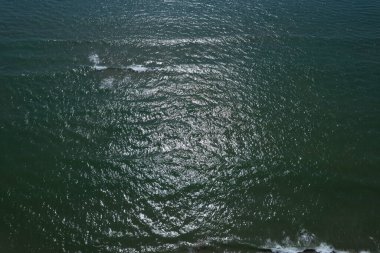 Dalgalanan denizin hava görüntüsü. Güneş ışığı yansımaları ve yumuşak dalgalar, rahatlatıcı ve doğal atmosfer..