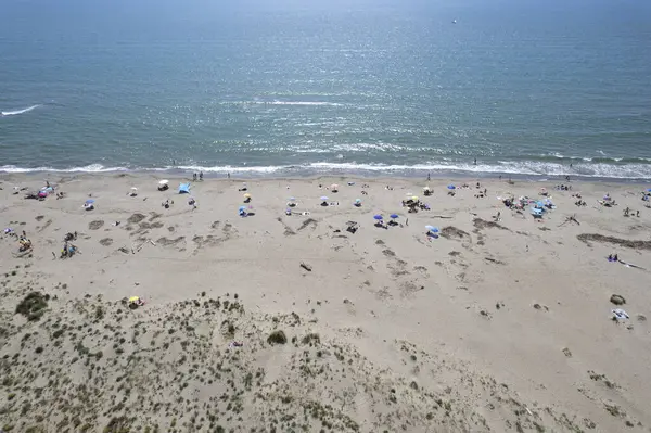 Yüzen ve renkli şemsiyeli doğal bir sahilin havadan görünüşü, yaz, özgürlük ve deniz kıyısında dinlenme.. 