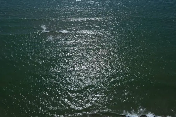 Dalgalanan denizin hava görüntüsü. Güneş ışığı yansımaları ve yumuşak dalgalar, rahatlatıcı ve doğal atmosfer..